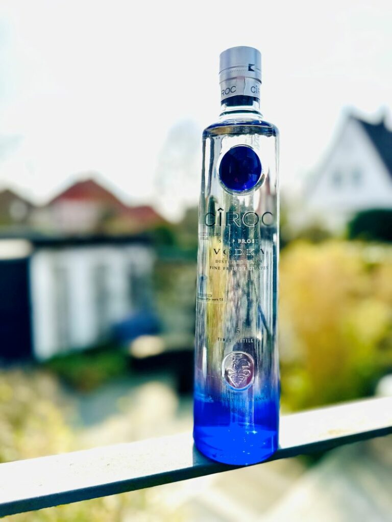 Eine Flasche Ciroc Vodka im Hintergrund ein Garten und ein Haus.